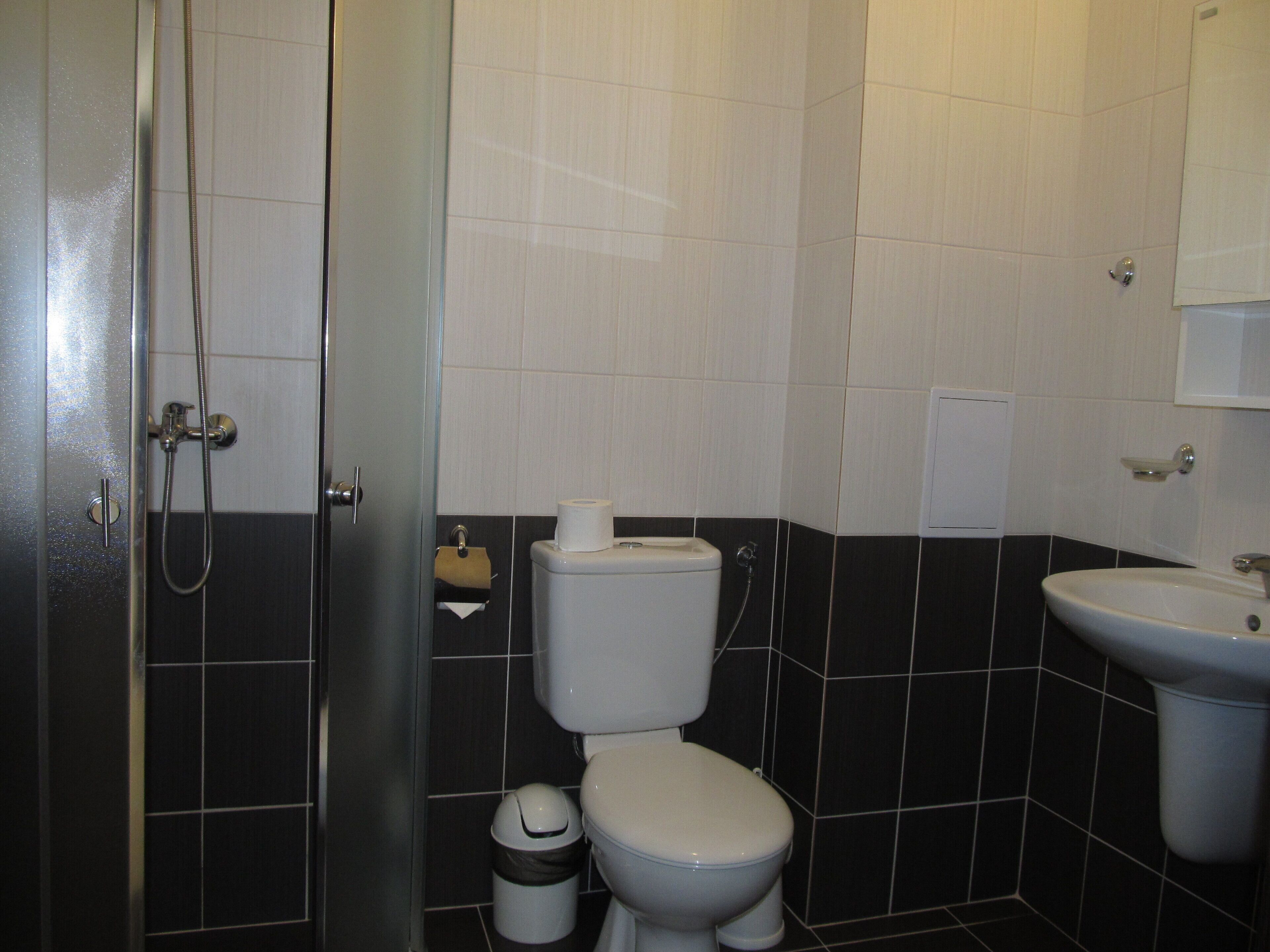 Et badeværelse med toilet, bidet, vask og en glasbrusekabine.