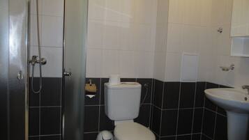 Et badeværelse med toilet, bidet, vask og en glasbrusekabine.