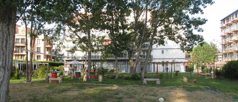 A park with trees, benches, and playground equipment.