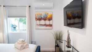 Moderni hotellihuone, jossa on sänky, lasinen pöytä, jonka päällä on kirahvia esittävä veistos, sekä kaksi taulua seinällä.