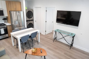 Une cuisine compacte avec un coin repas, un lave-linge et un téléviseur fixé au mur.