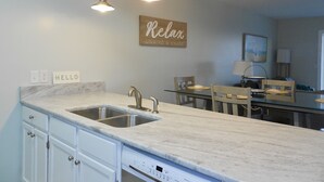 Una cocina moderna con encimera de mármol, pileta de acero inoxidable e iluminación colgante.