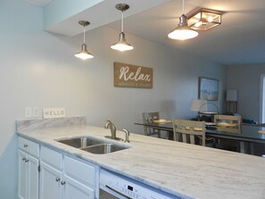 A modern kitchen with a marble countertop, stainless steel sink, and overhead lighting. - Peace of Paradise - Magnificent Gulf View! (Santa Rosa Beach)
