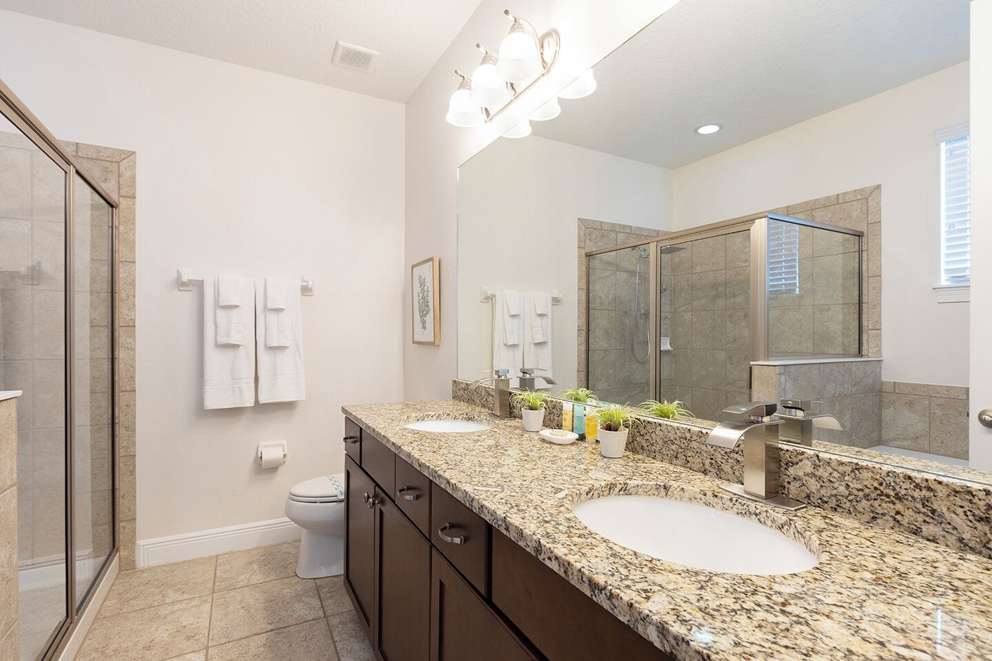A modern bathroom with two sinks, a shower, and a large mirror.