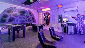 Une pièce équipée d’un baby-foot, de consoles de jeux et décorée sur le thème de Star Wars.