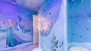 Une pièce ornée d’une fresque représentant un paysage hivernal, avec une porte blanche et une décoration en forme de bonhomme de neige.