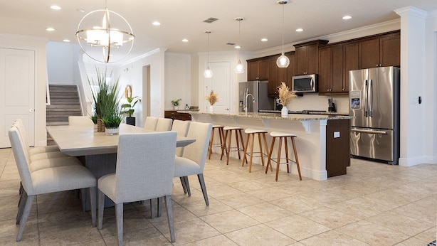 Une cuisine moderne dotée d’un îlot central, d’appareils électroménagers en acier inoxydable et de luminaires suspendus.