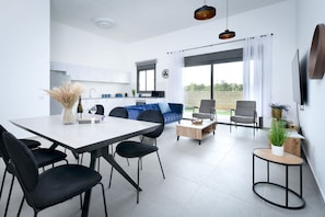 Ein modernes Wohnzimmer mit Essbereich, einer Couch und einer Küche im Hintergrund.