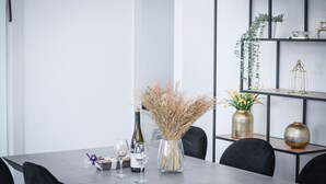 Ein zeitgemäßer Essbereich mit einem grauen Tisch, schwarzen Stühlen und einem schwarzen Metallregal mit Dekorationselementen.