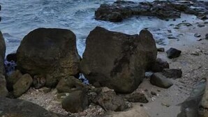Eine felsige Küstenlinie mit großen Felsen und ruhigem Meer.