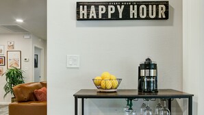 Ein Wohnzimmer mit Kaffeemaschine, Zitronenschale und einem 'Happy Hour'-Schild an der Wand.