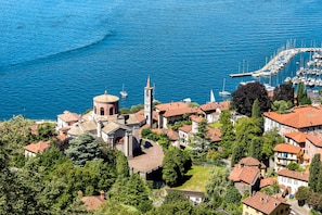 Une ville côtière qui se distingue par une église imposante, dotée d’un clocher, entourée de bâtiments résidentiels et bordée d’un port de plaisance où sont amarrés des bateaux.