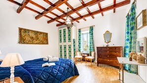 Un dormitorio con una cama, un aparador, una silla, una mesa, una lámpara y un cuadro.
