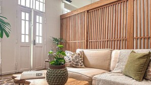 Una sala de estar acogedora con un revestimiento de madera, un sofá color beige, un tapete estampado y una mesa de centro de madera con una planta en maceta.