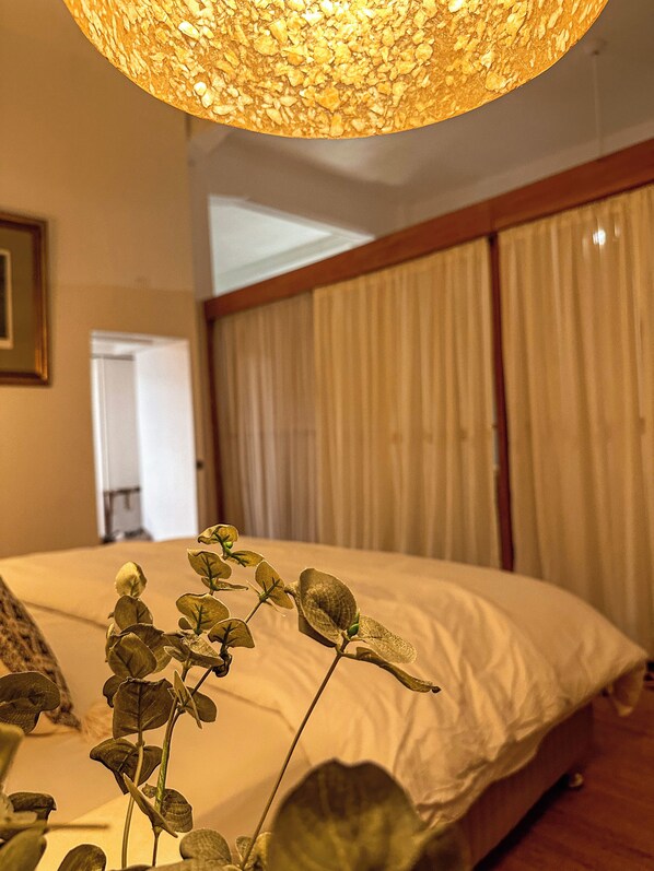 Un dormitorio con cama, lámpara colgante y una planta.