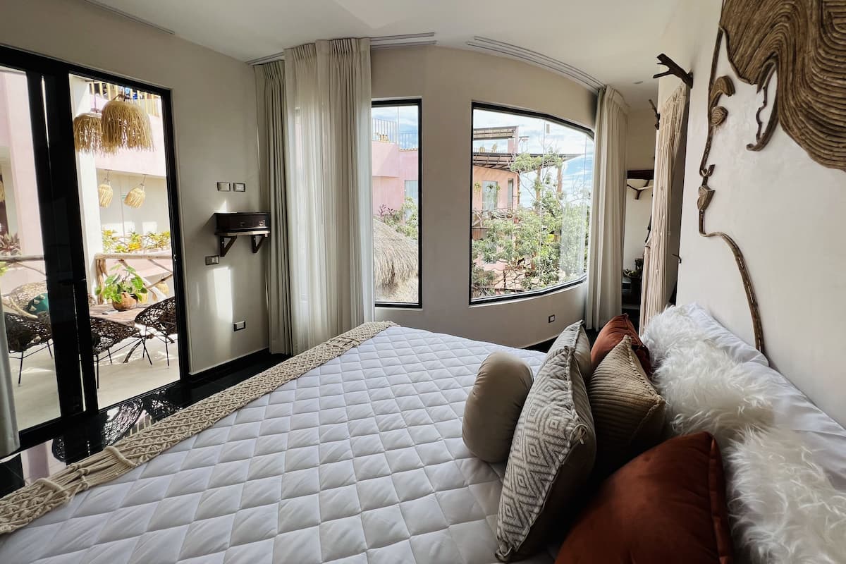 Un dormitorio con una cama grande, vistas al exterior y un balcón.
