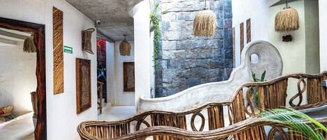 A modern interior with a stone wall, wicker furniture, and hanging lights.