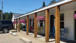 A covered porch with wooden pillars, outdoor seating, and hanging flower baskets.