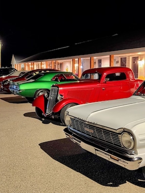 Uma fileira de carros antigos estacionados em frente a um edifício com janelas iluminadas.