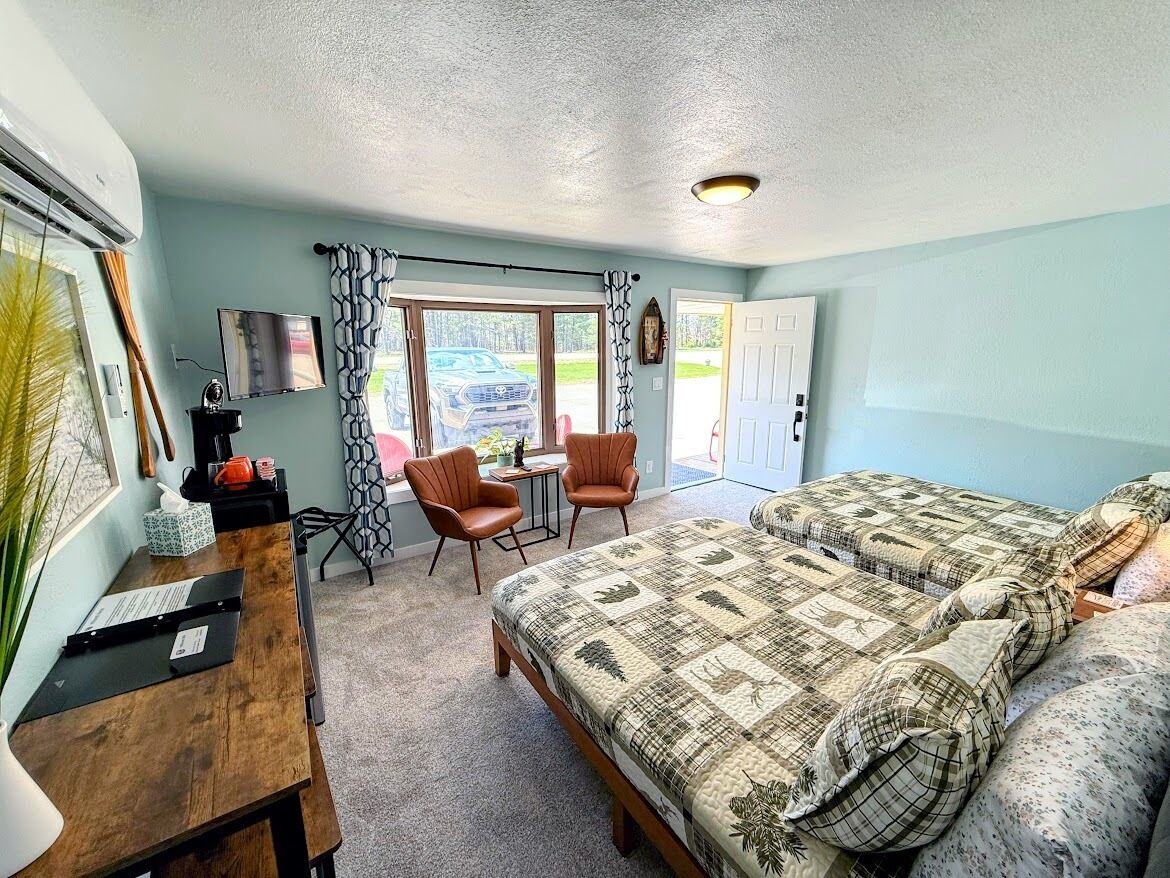 A bedroom with a large bed, a desk with a chair, a TV, and a window with curtains.