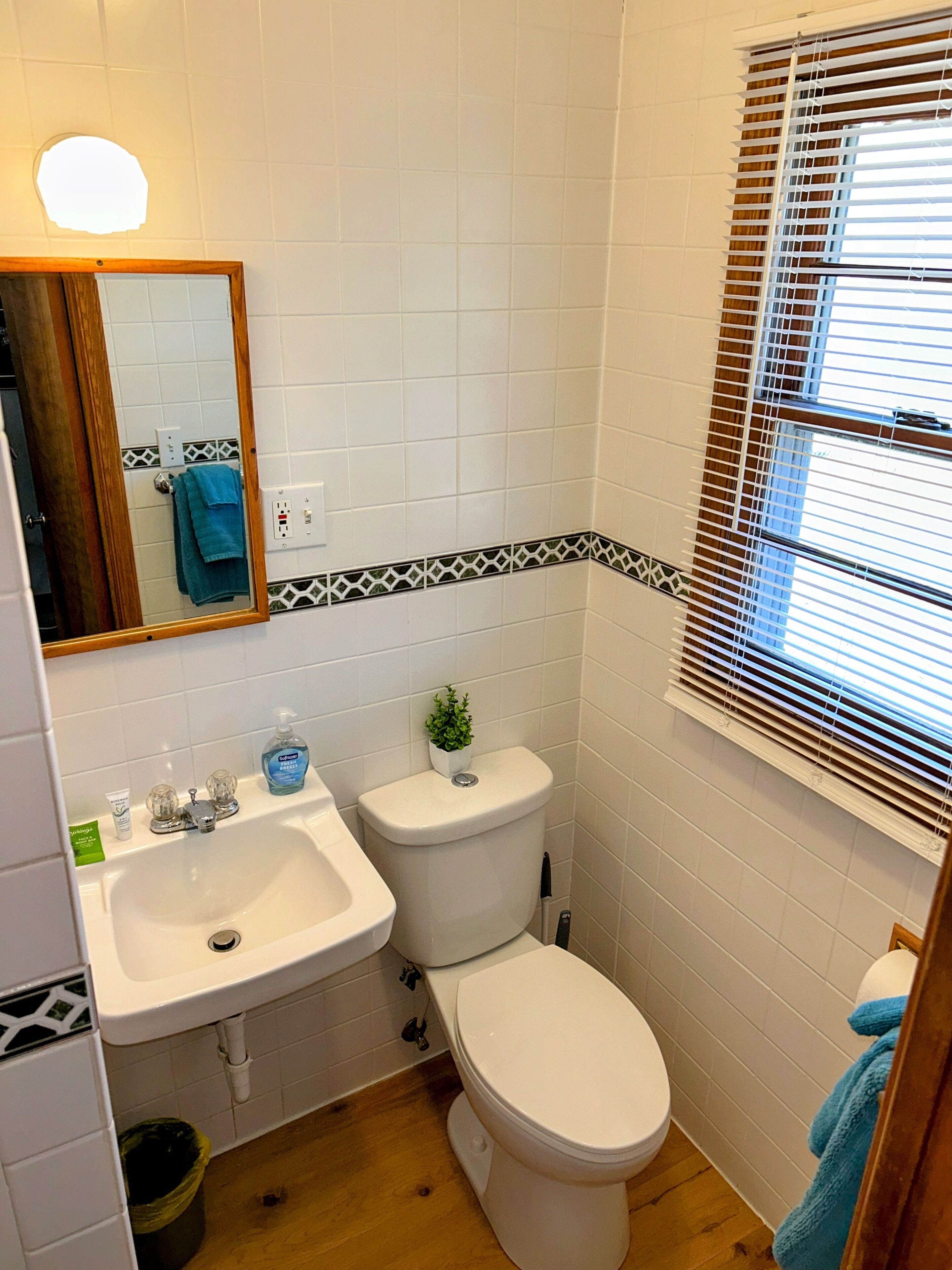 A bathroom with a sink, toilet, and window with blinds.