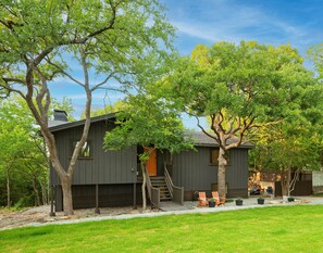 A modern house with a wooden deck, a staircase leading to the entrance, and a small outdoor seating area with chairs and tables. - NEW! ♦ Fun & Modern Lake Retreat ♦ Near Marina! (Pottsboro)