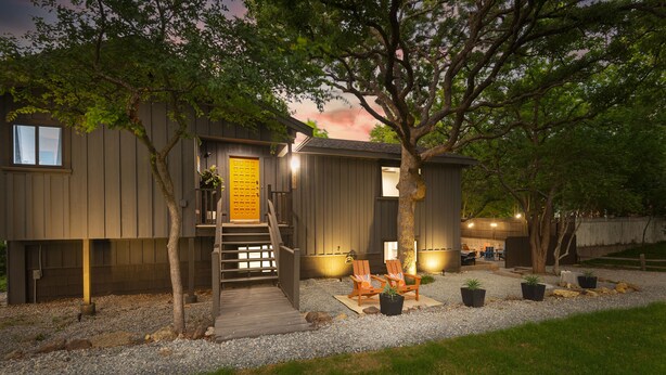 A modern house with a wooden deck, two outdoor chairs, and potted plants. - NEW! ♦ Fun & Modern Lake Retreat ♦ Near Marina! (Pottsboro)