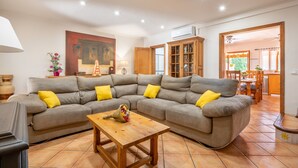 A living room with a sectional sofa, wooden coffee table, and a painting on the wall. - Holiday Home Villa Ca Na Campins with Mountain View, Pool, Terraces & Wi-Fi (Campanet)