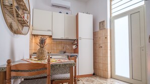 A kitchen with a dining table, chairs, a refrigerator, and a window. - Holiday Home "Tyndaris" with Wi-Fi & Air Conditioning (Oliveri)