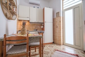 Une cuisine équipée d’une table à manger, de chaises, d’un réfrigérateur et d’une fenêtre.