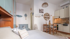 A bedroom with a bed, a small desk, and a kitchenette. - Holiday Home "Tyndaris" with Wi-Fi & Air Conditioning (Oliveri)