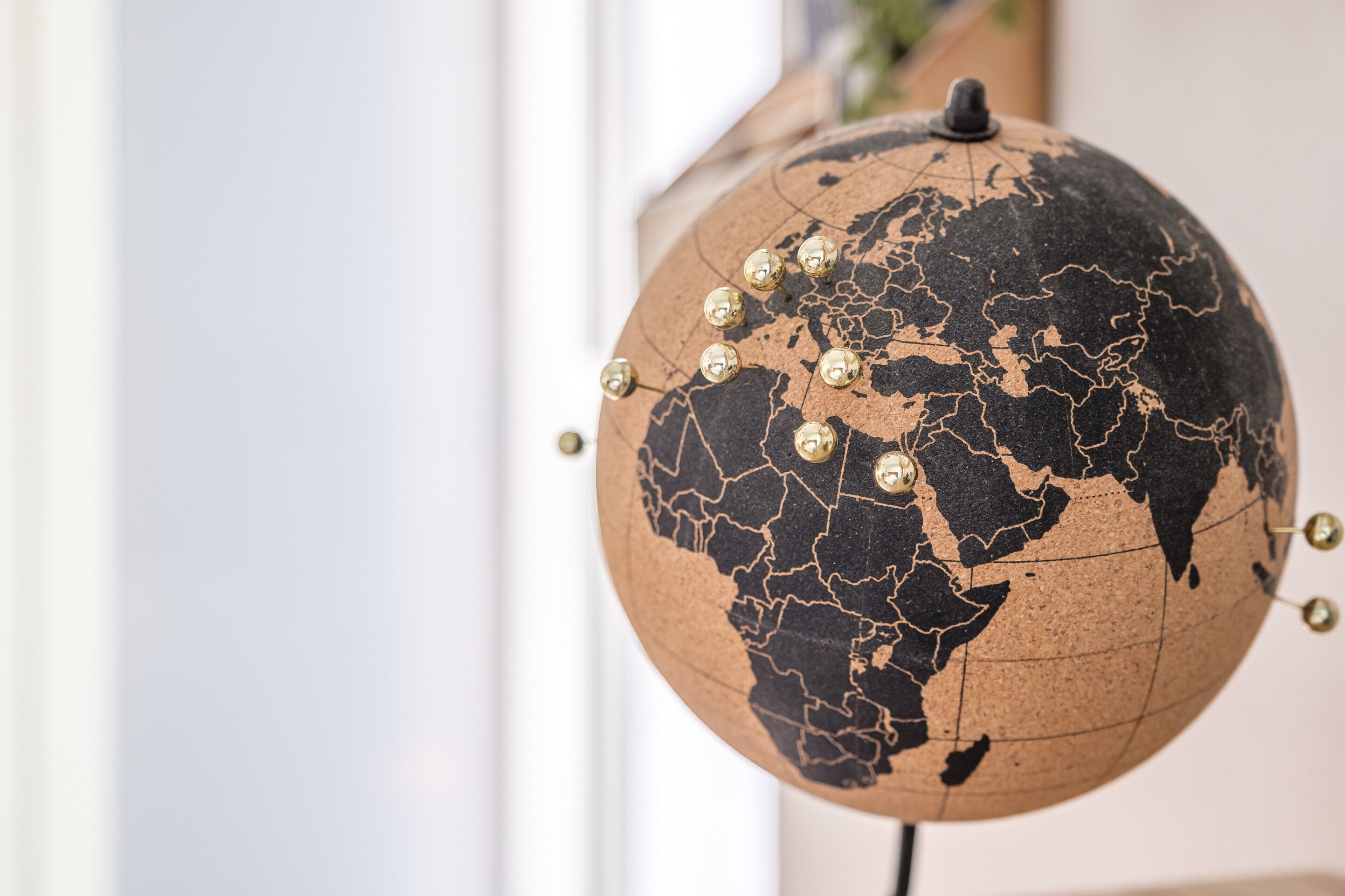 Un globe dont la surface est craquelée et ornée de petites pointes dorées, fixé sur un socle.