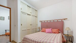 Ein Schlafzimmer mit einem Bett, einem Kleiderschrank, einem kleinen Tisch und einem Sessel.
