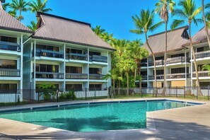 A hotel with multiple balconies, a swimming pool, and palm trees. - Cozy 2br 1ba Apt in Waiakea Villas with work space (Hilo)