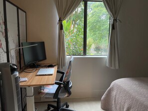 Una stanza con una scrivania, un computer, una sedia e un letto.
