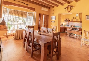 Un coin repas avec une table et des chaises en bois, une cuisine équipée d’une cuisinière et de placards, et une fenêtre donnant sur un paysage verdoyant.