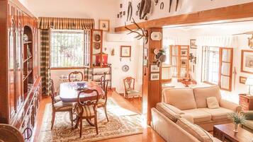 Una sala de estar acogedora con un sofá, una mesa de comedor con sillas y una zona de cocina con ventanal.