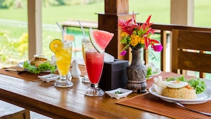 A wooden table with drinks, a salad, and a plate of rice with vegetables.