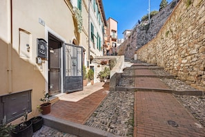 A narrow street with stone walls, a paved path, and buildings with doors and windows.