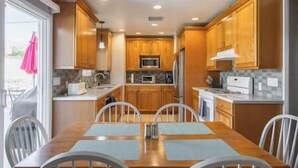 Una cocina compacta con armarios de madera, un microondas, un refrigerador y una mesa de comedor con sillas.