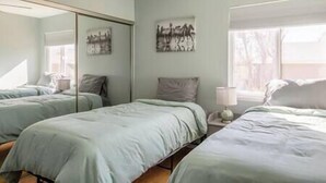 Un dormitorio con dos camas, un espejo grande y obras de arte en la pared.