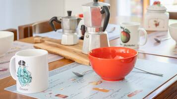 A kitchen counter with a coffee maker, a red bowl, and a spoon on a placemat.