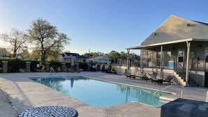 A swimming pool with lounge chairs and a covered seating area.