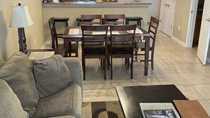 A living room with a sofa, a coffee table with a magazine, and a dining area with a table and chairs.