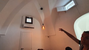 A room with a sloped ceiling, an air conditioning unit, a door, and a hanging light fixture. - Holiday Home "Villa Adriana" with Terrace & Wi-Fi (Pantelleria)