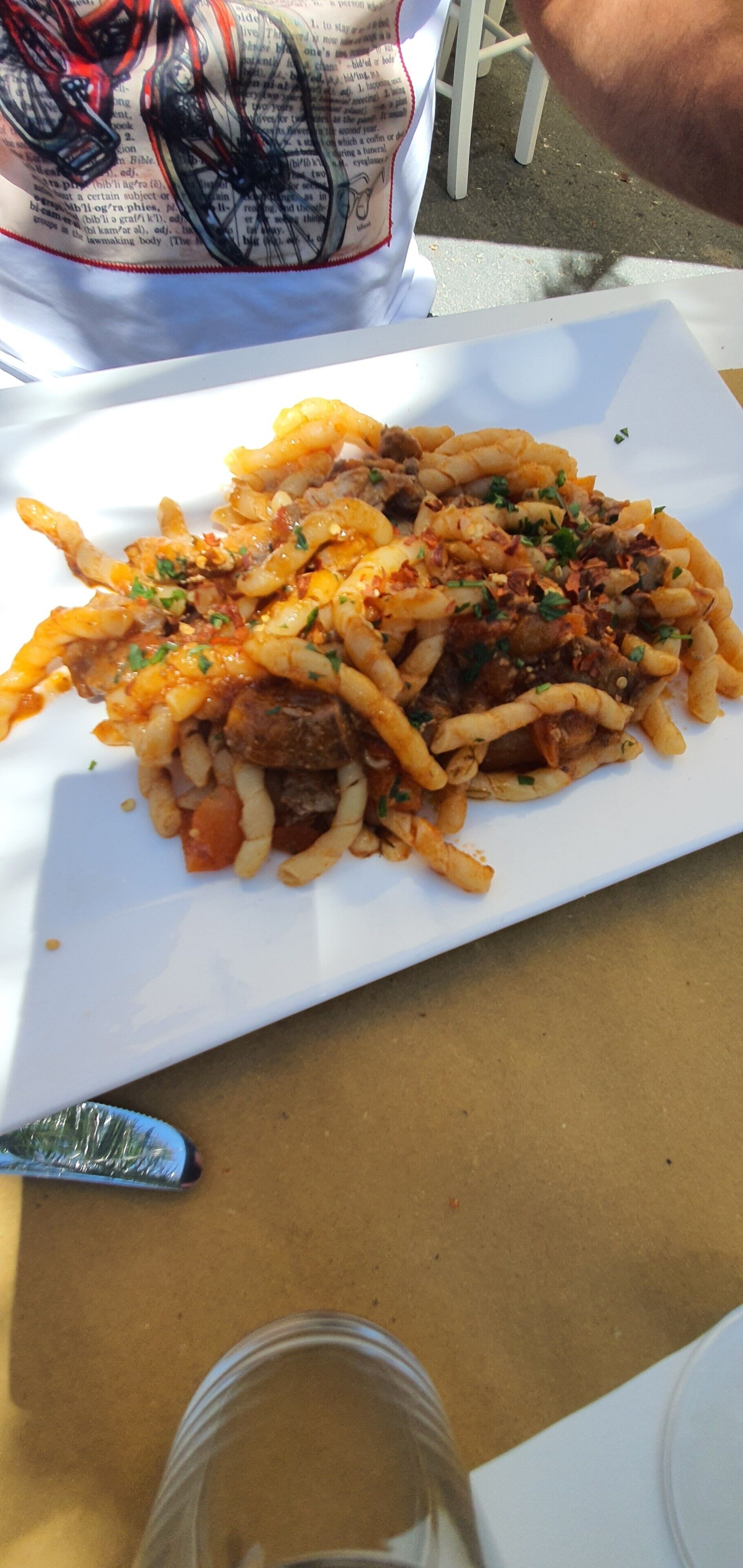 A plate of food with fries and meat, a white tablecloth, and a plastic cup.