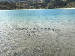 A beach with clear water and the word 'Sanitierra' written in the sand.