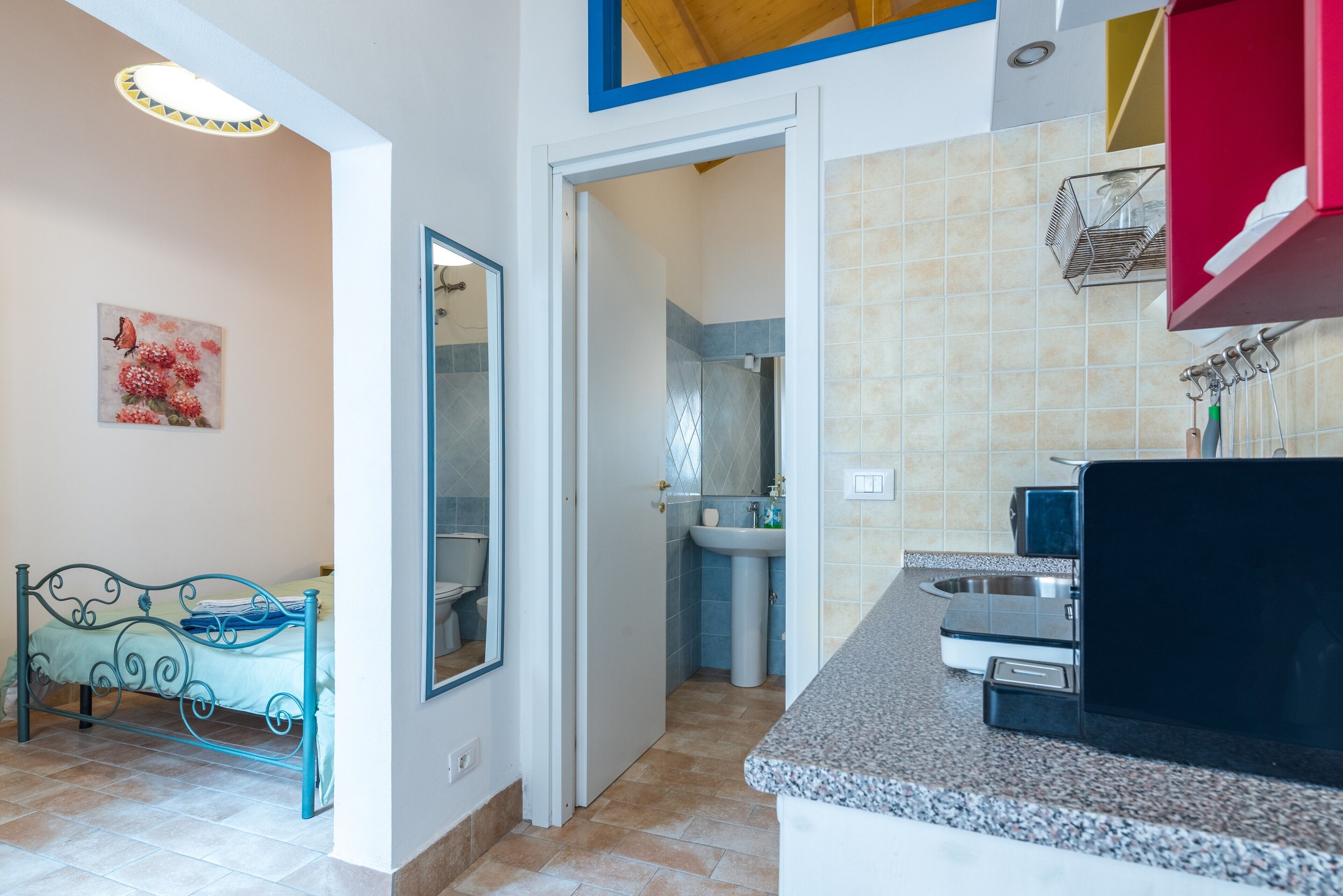 A bedroom with a bed, a bathroom with a toilet and sink, and a kitchen with a countertop and sink.