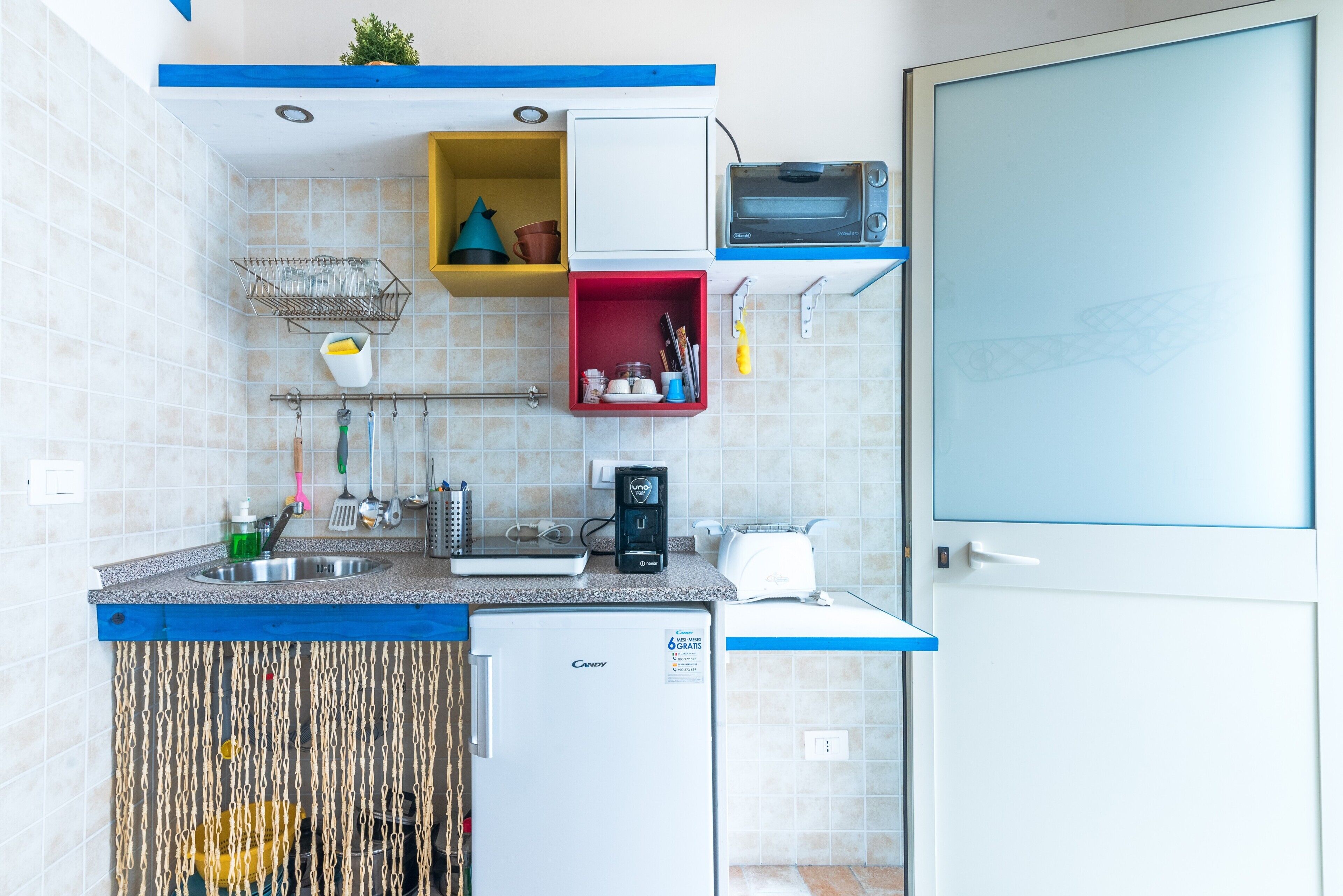 A compact kitchen with a sink, a toaster, and a small refrigerator.