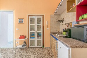 A kitchen with a microwave, a kettle, and a sink.